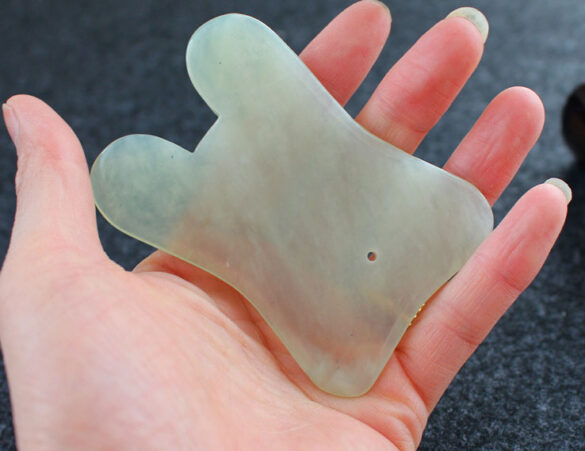 Gua Sha en jade dans main Gua sha dans main